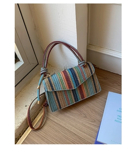 Detail of colorful rainbow woven handbag with gold hardware and woven rope handle