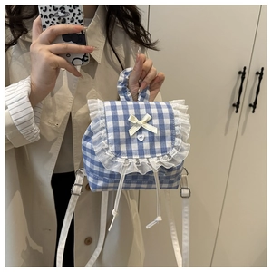 Detail of blue gingham mini backpack featuring white lace ruffles and satin bow decoration
