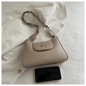 Detail of khaki leather shoulder bag featuring metal bow and woven strap with phone for scale