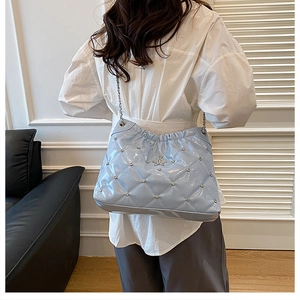 Detail of blue quilted bucket bag featuring star logo, silver studs and chain strap