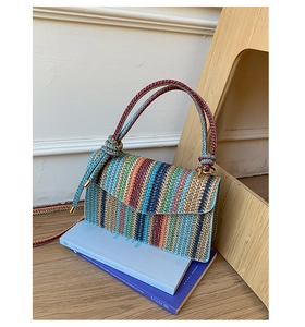 Detail of colorful woven shoulder bag with rope handles and textured stripe patterns