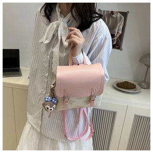 Detail of pink and white embossed mini backpack featuring a plush bear charm on the side