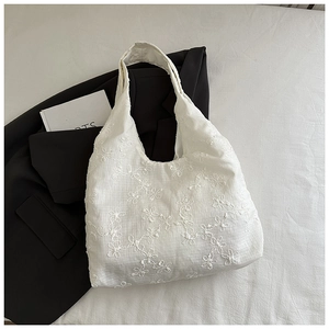 Détail du sac cabas en toile blanche avec broderie florale délicate et texture en dentelle
