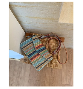 Top view of a woven crossbody bag with colorful stripes on a wooden texture bench