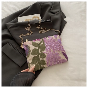 Détail de broderie florale en paillettes sur un sac bandoulière tissé blanc pour femme