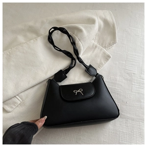 Detail of black matte leather shoulder bag with silver bow accent and woven strap detail