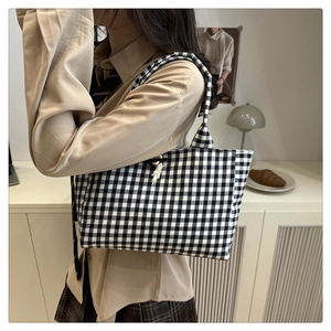 Dettaglio della borsa tote in tela a quadretti bianchi e neri con nodo decorativo bianco