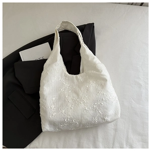 Gros plan détaillé de la broderie de fleurs en dentelle blanche sur un sac fourre-tout