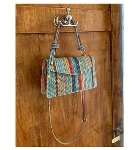 Detail of bohemian colorful striped woven crossbody bag with gold chain and rope handle