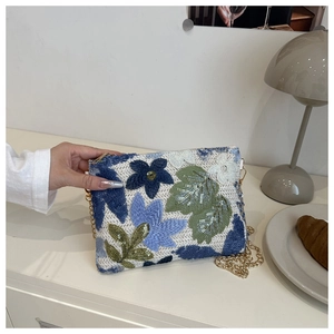 Détails de broderie de fleurs bleues à paillettes et chaîne dorée sur la pochette