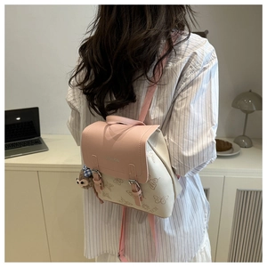 Detail of pink flap backpack featuring butterfly prints and a cute plush bear charm
