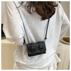 Dettaglio mini borsa a tracolla in pelle nera testurizzata con doppie fibbie decorative