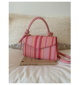 Macro detail of multicolored striped woven bag with cylinder handle on aesthetic book