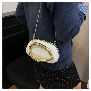 Detail of white mini ball-shaped clutch featuring a large gold metal ring and chain strap