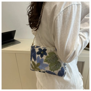 Détail de la broderie florale et des paillettes sur un sac à bandoulière blanc