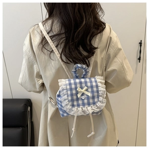 Detail of blue plaid mini backpack with white lace trim and yellow bow accent