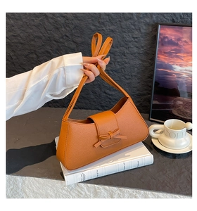 Detalle del bolso de hombro color caramelo con lazo decorativo y solapa de diseño retro
