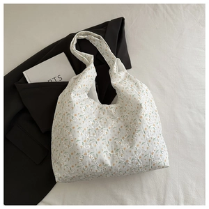 Détail de la broderie en dentelle florale blanche sur un sac cabas en toile robuste