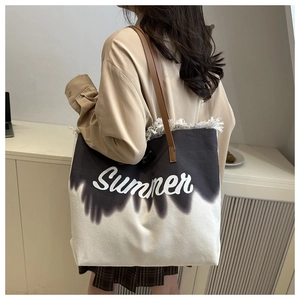 Detail of canvas tote bag with fringe edge, summer lettering, and leather straps