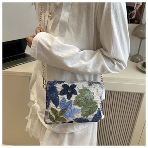 Vue détaillée d'un sac bandoulière blanc orné de broderies florales et de paillettes