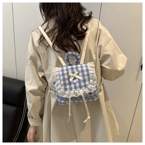 Blue plaid backpack with white lace ruffles and bow detail shown on a female model