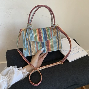 Detail of multi-color striped woven bag with golden clasp and adjustable shoulder strap