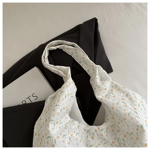 Détail de la broderie en dentelle florale et motif fleurs jaunes sur le sac en toile