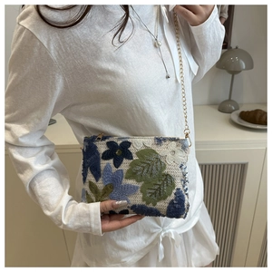 Close-up of sequined floral embroidery and gold chain strap on the small handbag