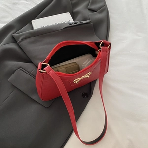 Red lychee grain underarm bag with gold bow clasp on grey suit jacket