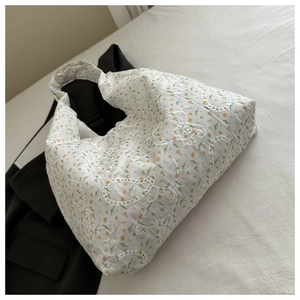 Détail de la broderie florale en dentelle et des œillets sur le sac cabas en toile