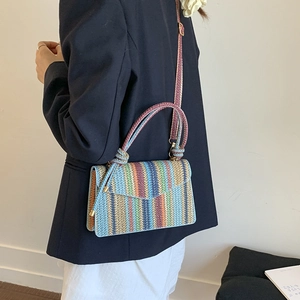 Detail of colorful striped woven shoulder bag with envelope closure and gold hardware