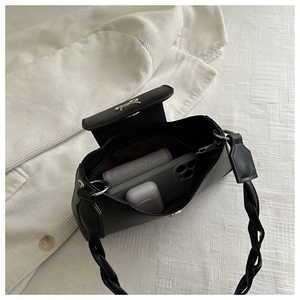 Detailed view of black shoulder bag with braided strap and interior storage capacity