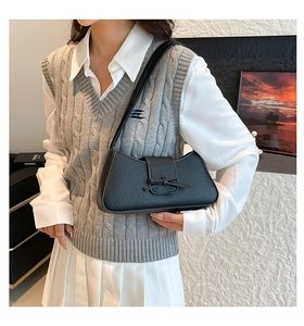 Detalle de un bolso baguette negro con lazo y textura de cuero de lichi