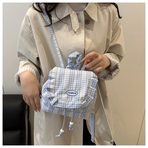 Detailed view of light blue gingham backpack with ruffled edges and drawstring closure