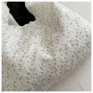 Détail du sac en toile beige avec imprimé floral et broderie en dentelle blanche