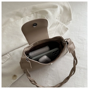 Spacious interior of beige leather shoulder bag showing storage for phone and earbuds