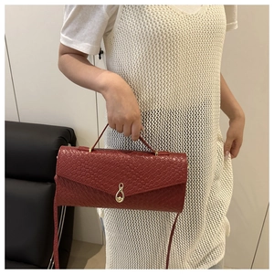 Dettaglio borsa a mano rossa intrecciata con fibbia a infinito dorata e tracolla rimovibile