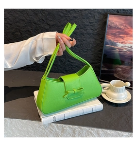 Detalle del bolso baguette verde neón con textura de grano lichi y lazo de cuero