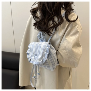 Close-up of blue gingham mini backpack with ruffled edges and embroidered fashion logo
