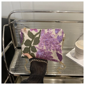 Détails de broderie de fleurs à paillettes violettes et chaîne dorée du sac beige