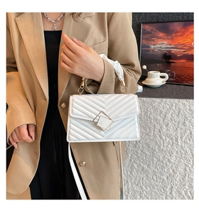 Close-up of white quilted handbag with silk scarf handle and golden square metal clasp
