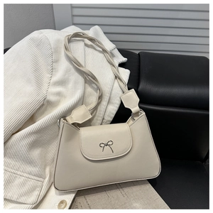 Detail of cream shoulder bag with metallic bow buckle and twisted woven strap design