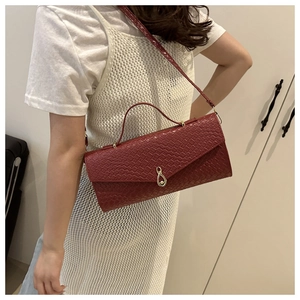 Dettaglio della borsa a tracolla rossa intrecciata con elegante chiusura girevole dorata