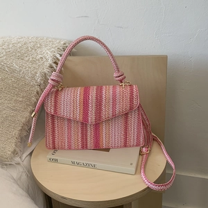 Close-up of pink and orange striped woven bag with knot handle and strap on stool