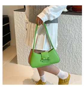 Detalle del bolso baguette verde con lazo decorativo y textura de cuero sintético