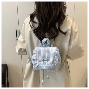 Close-up of blue lace plaid backpack featuring ruffle details and drawstring bead charms