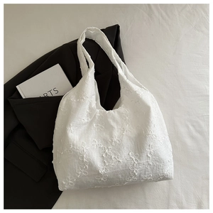 Détail de la broderie florale en dentelle sur le sac cabas blanc au style élégant