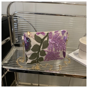 Détail de broderie florale en paillettes sur toile beige avec chaîne dorée