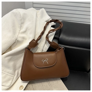 Detail of coffee brown leather shoulder bag with silver metal bow and woven strap