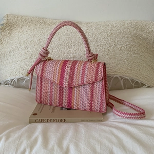 Detail of pink wavy knit bag with a knotted handle on a book in a cozy setting